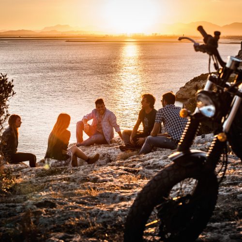 Five motorcycling friends taking a break on coast at sunset, Cagliari, Sardinia, Italy