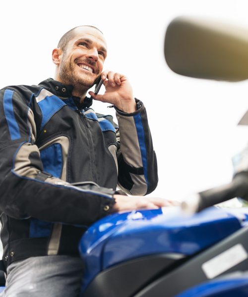 Handsome biker using mobile phone in the street.