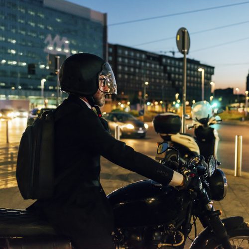 Mature businessman outdoors at night, riding motorcycle