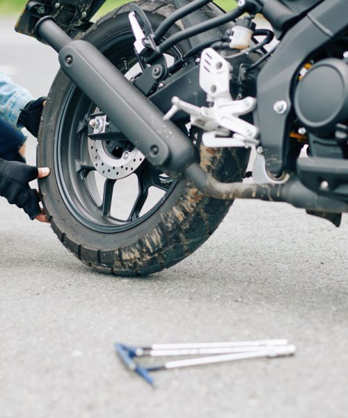 Close-up image of man replacing damaged tire of motorcycle