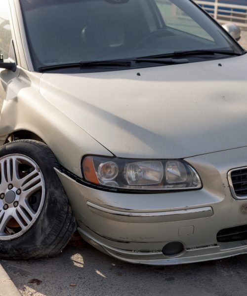 Severe damage to grey car's side after a collision, showcasing a crumpled door and detached bumper. Ideal for use in insurance claims, automotive repair tutorials, and road safety awareness materials