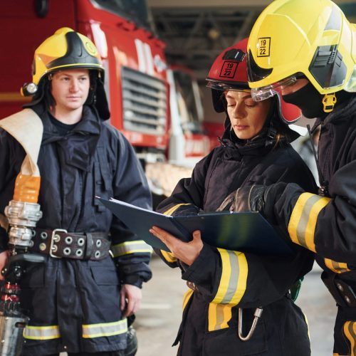 With notepad. Group of firefighters in protective uniform that is on station.